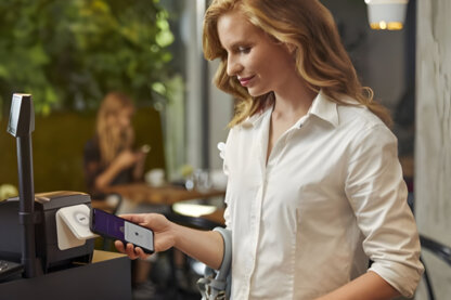 A woman paying with her phone. A woman paying with her phone.