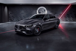 A black Mercedes car parked in a dark room with a streak of red light behind it. A black Mercedes car parked in a dark room with a streak of red light behind it.