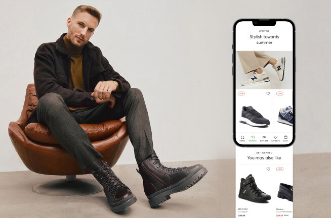 A man sitting on a chair, showing off his shoes. Next to him, there's a smartphone opened on the eobuwie app.